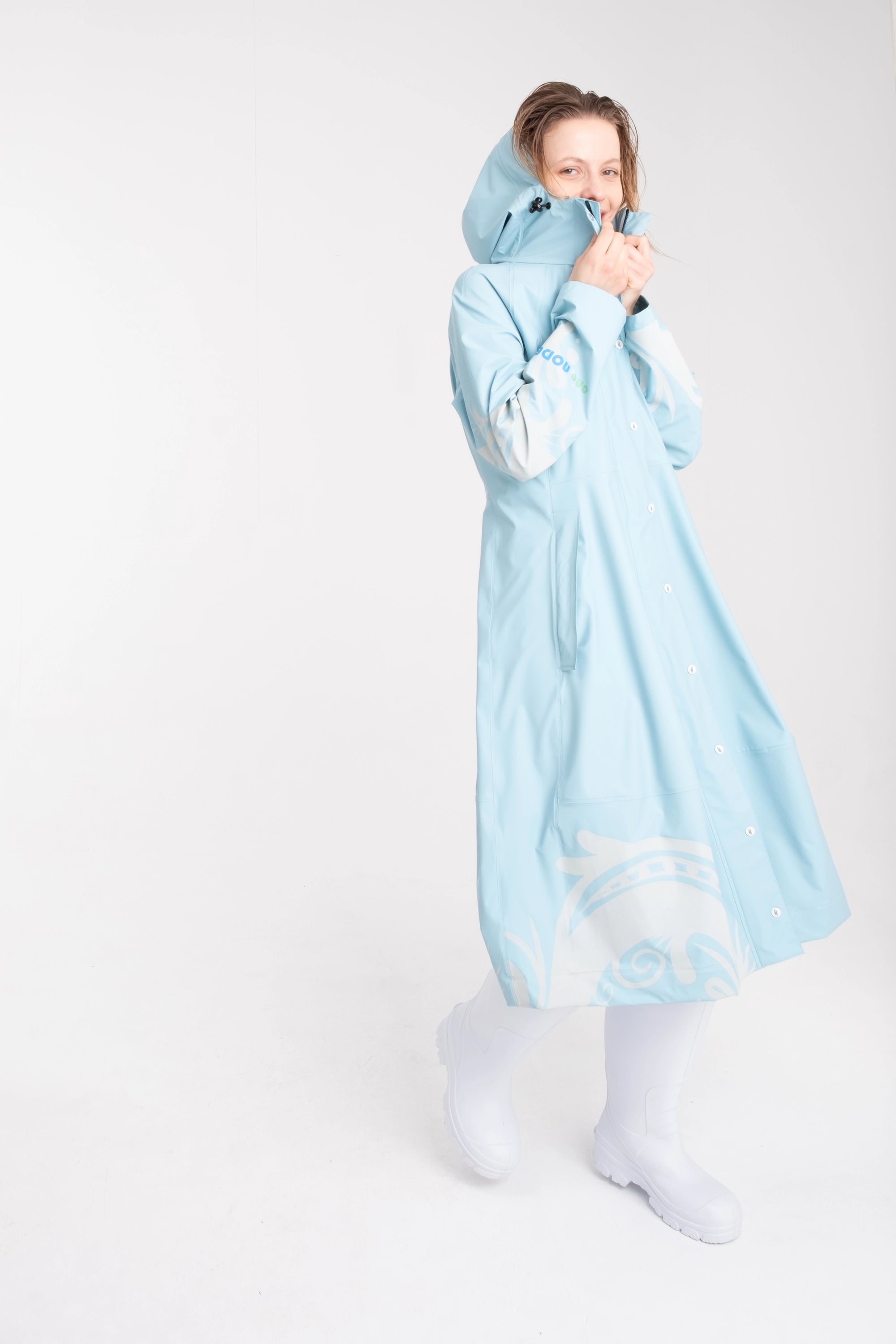 One NODE Scandinavian raincoat for women in sky blue with reflective details – a waterproof, lightweight, and eco-conscious jacket made with sustainable materials for enhanced visibility and style in Nordic weather.