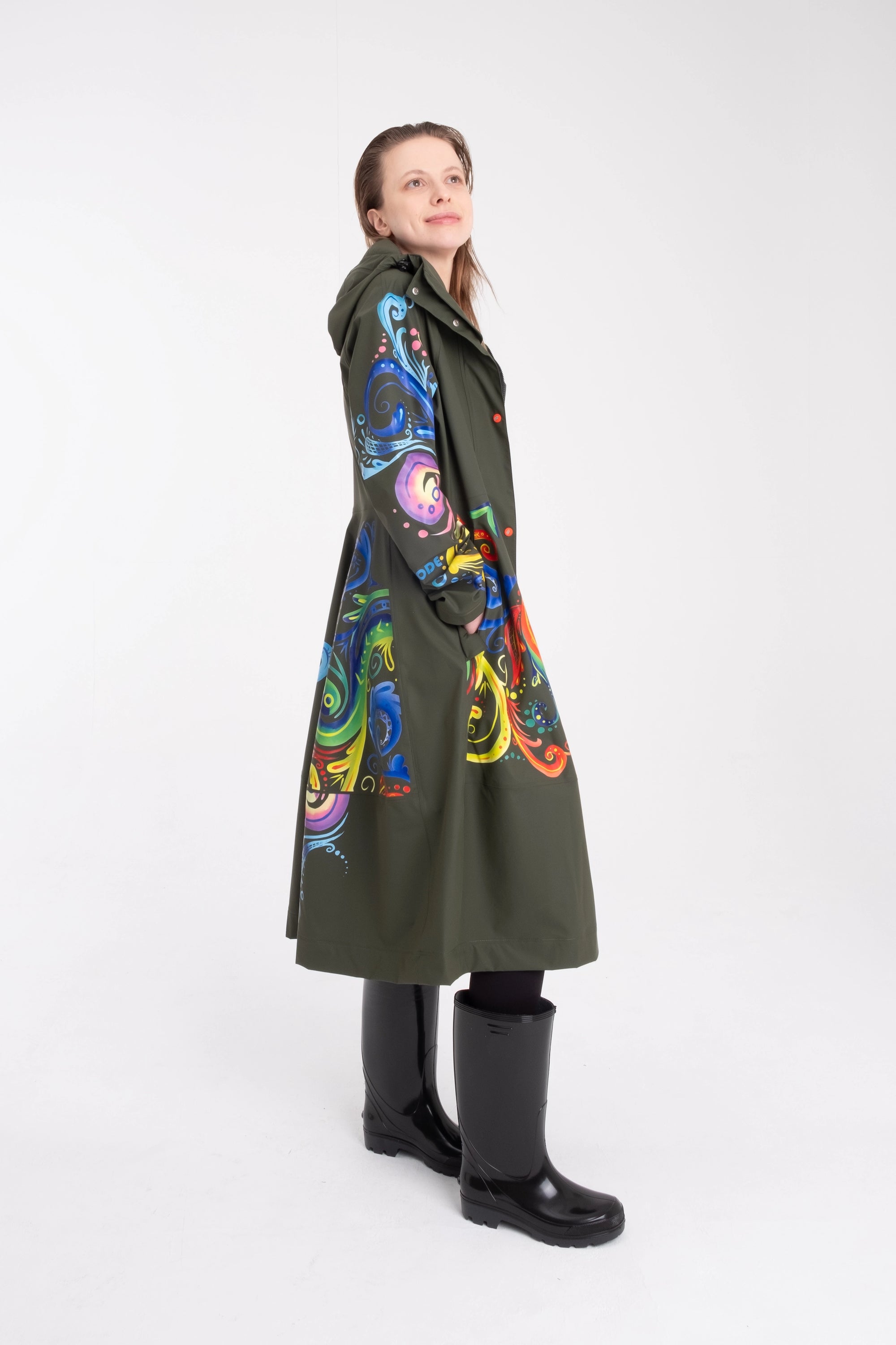 One NODE Scandinavian raincoat for women in olive green with intricate rosemaling pattern – a waterproof, lightweight, and eco-conscious jacket made with sustainable materials for Nordic weather.