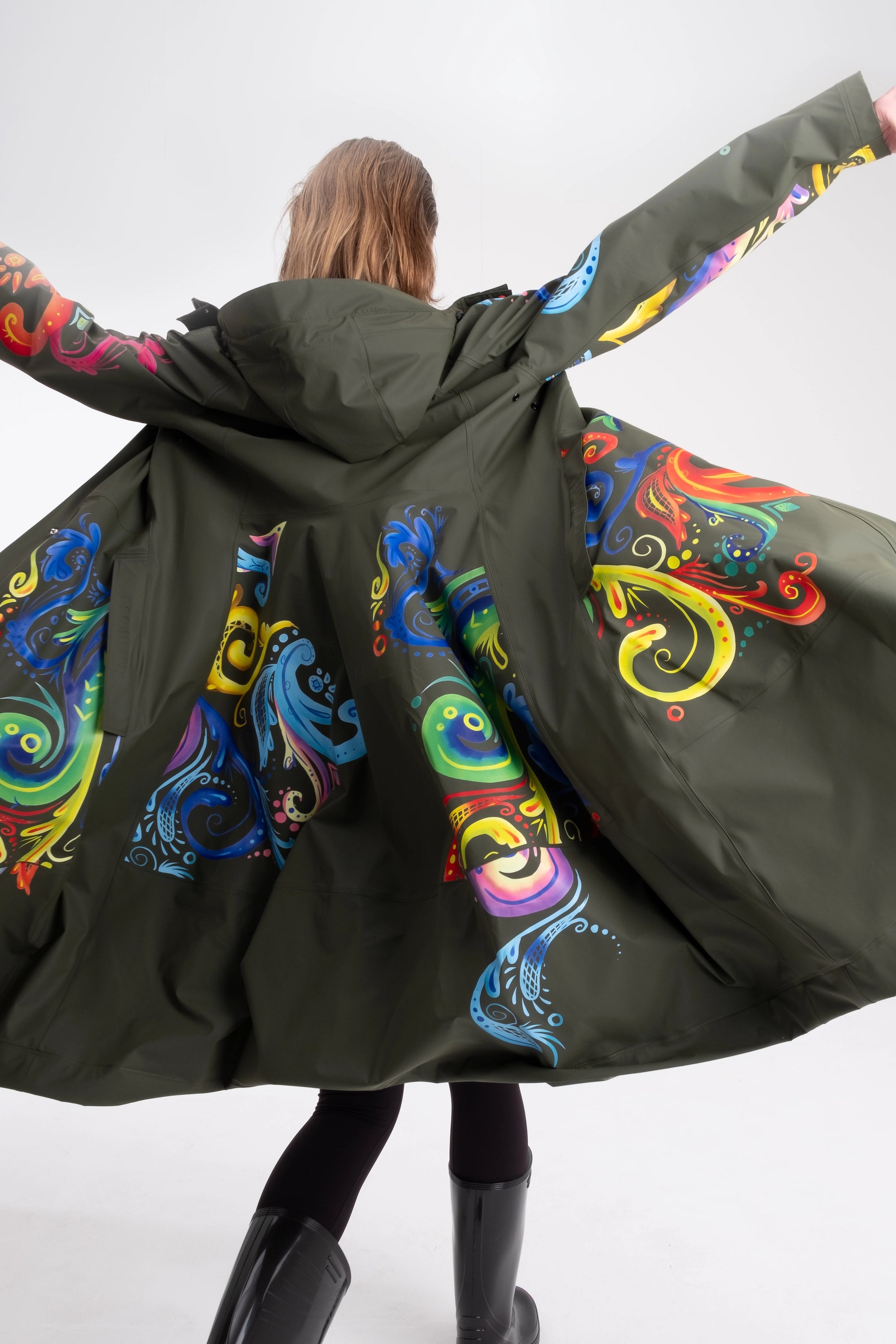 One NODE Scandinavian raincoat for women in olive green with intricate rosemaling pattern – a waterproof, lightweight, and eco-conscious jacket made with sustainable materials for Nordic weather.